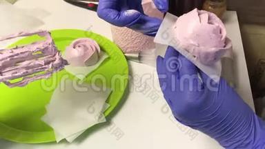 一个女人把一朵棉花糖玫瑰放在托盘上。 桌子上有一个容器，里面有棉花糖和其他制作棉花糖的工具